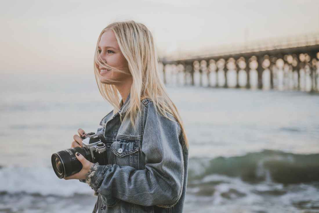 woman taking pictures beside ocean
