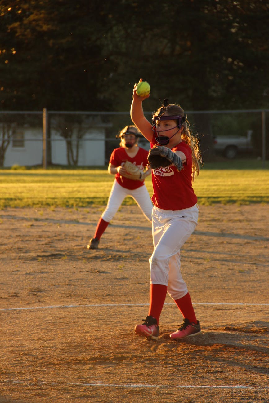 girl wearing baseball mitts holding soft ball
