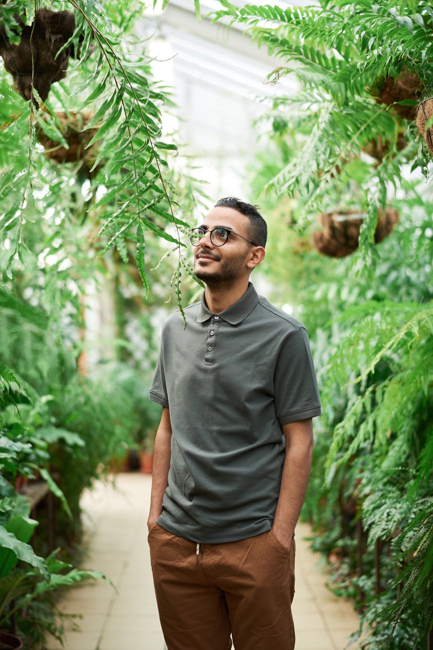 photo of man standing near green leafed plants