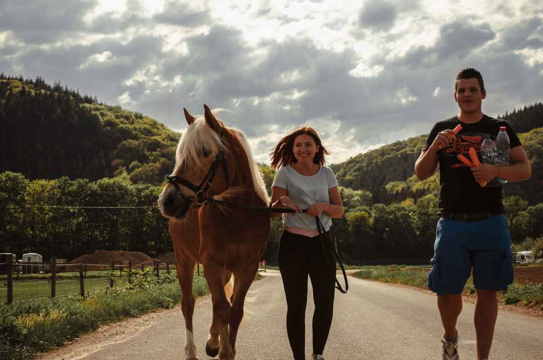 woman walking between horse and a man